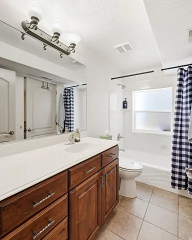 Bathroom featuring a single vanity with a white countertop, wood-finish cabinetry, and a full-width mirror