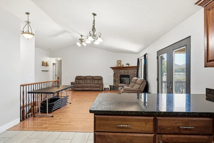 Open concept living space featuring vaulted ceilings, wood-finish flooring, and a stone-faced fireplace