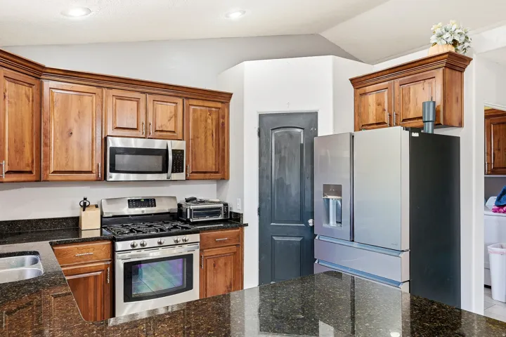 Kitchen featuring wood-finish cabinetry, dark speckled countertops, and stainless steel appliances