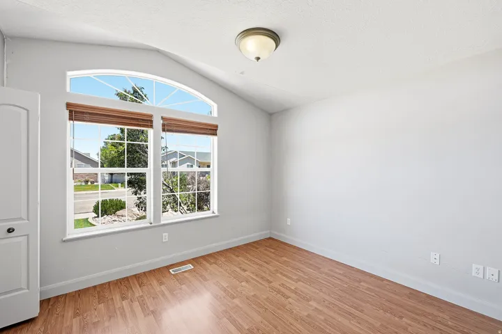 Arched transom window above a large picture window with wood-finish blinds