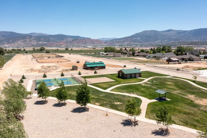 Expansive property featuring multiple pickleball courts, a manicured green space, and a covered picnic area