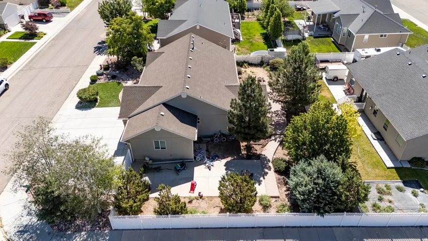 Expansive backyard featuring mature trees, concrete patio space, and a white picket fence