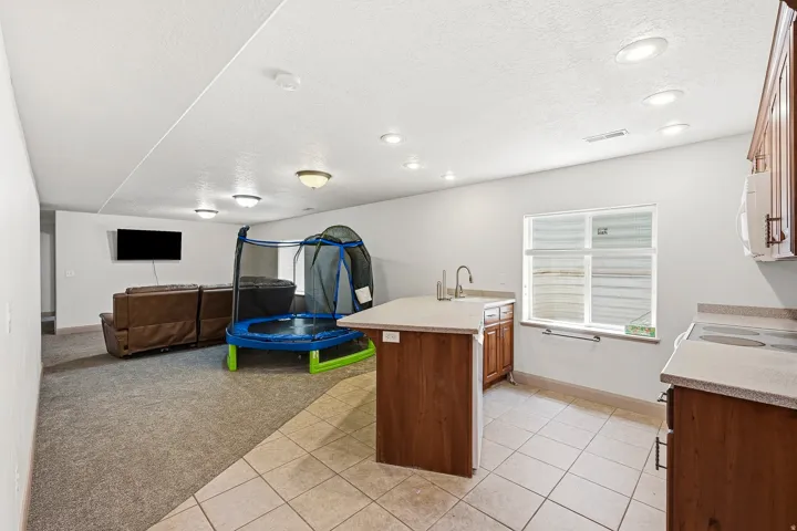 Open-concept recreational space featuring recessed lighting, a window, and a mixed flooring of carpet and tile