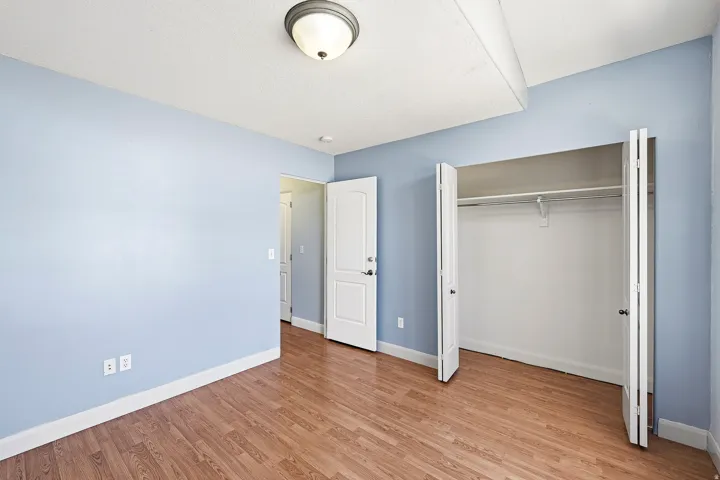 Bedroom with wood-finish flooring, light blue walls, and a white ceiling