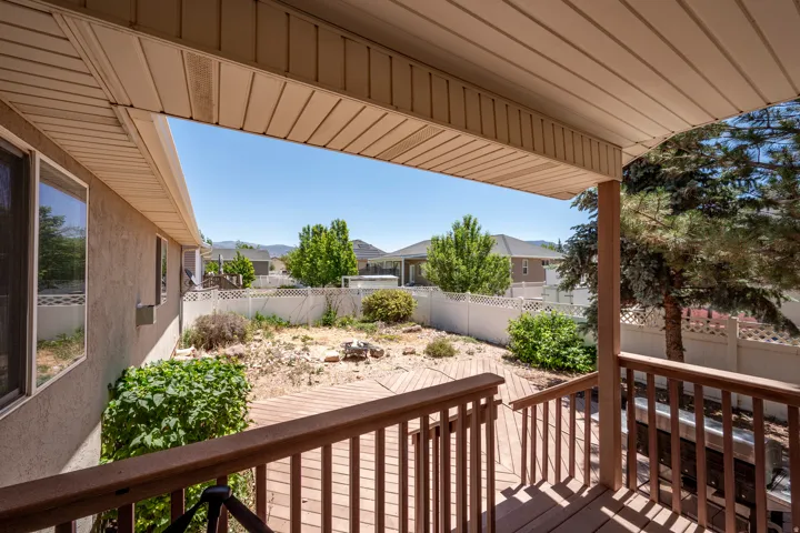 Spacious outdoor deck with natural wood-tone railing and covered patio