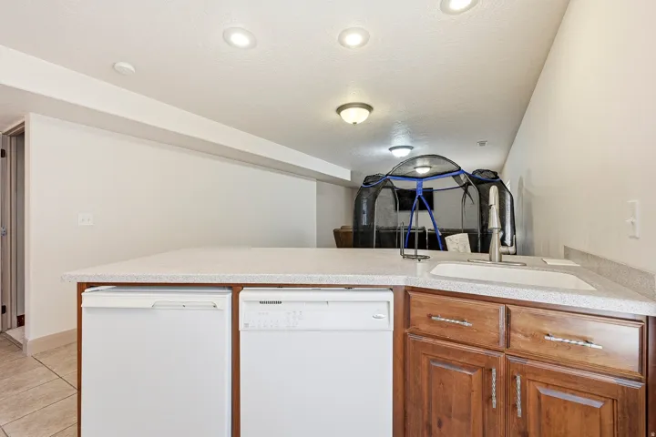 Kitchenette featuring a white sink, chrome faucet, and integrated dishwasher