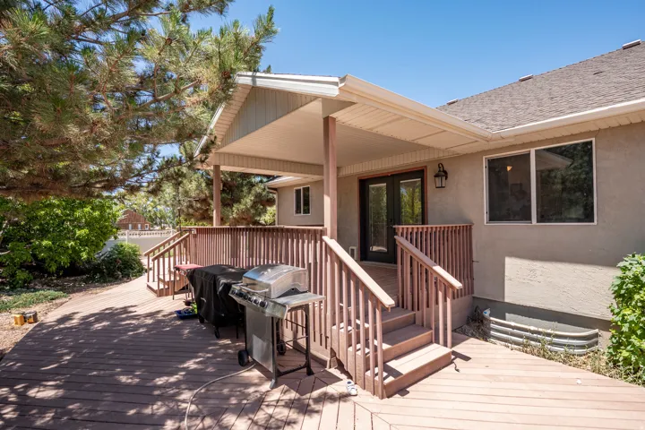 Expansive wood-finish deck featuring a covered patio, railing, and staircase