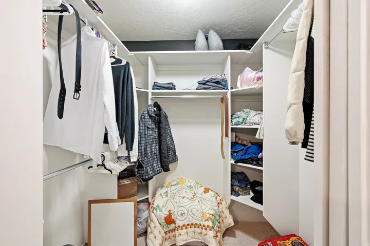 White walk-in closet featuring multiple shelving units and hanging rods