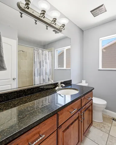 Bathroom vanity featuring a dark speckled countertop, an undermount sink, and wood-finish cabinetry with silver-tone hardware