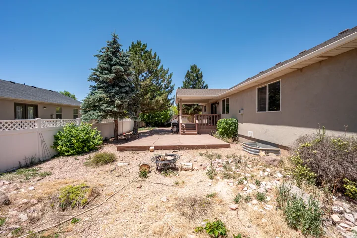 Expansive outdoor space featuring a covered wood deck, an additional concrete patio, and a white lattice-top fence