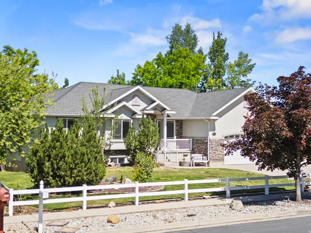 Single-story residence featuring a gray exterior with stone accents and a white railing porch
