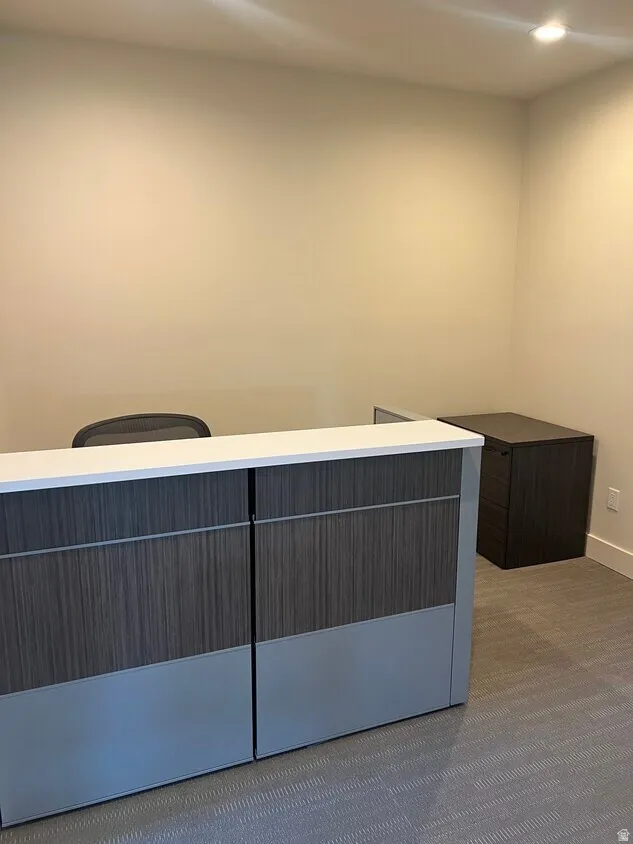 Reception area featuring a wood-finish and matte gray reception desk with a white countertop