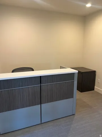 Reception area featuring a wood-finish and matte gray reception desk with a white countertop