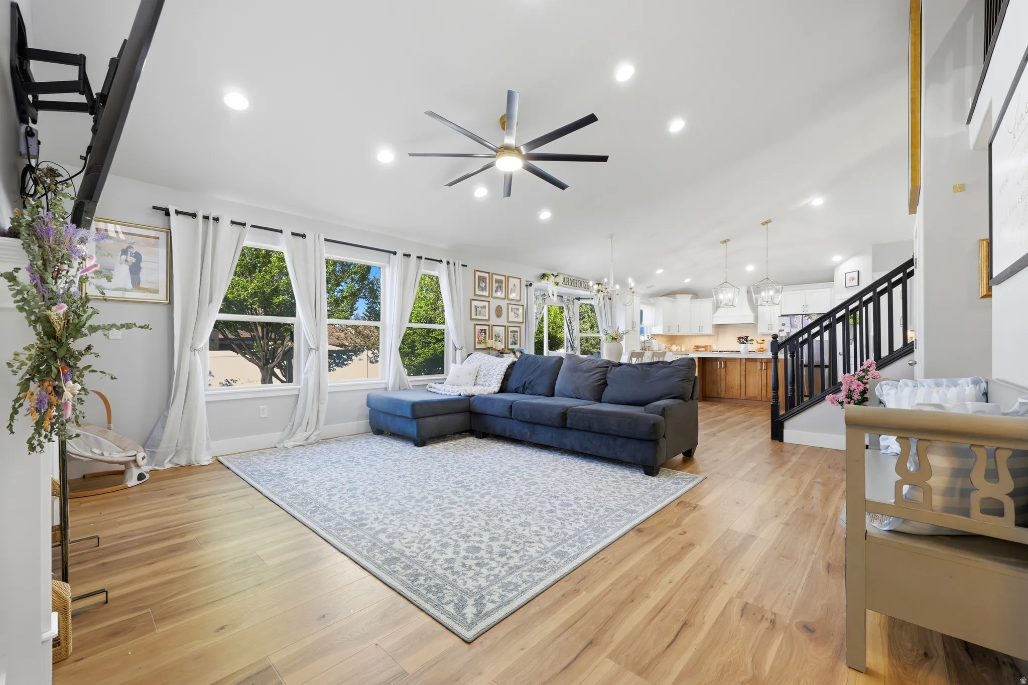 Open-concept living area with wood-finish flooring, recessed lighting, and a contemporary ceiling fan