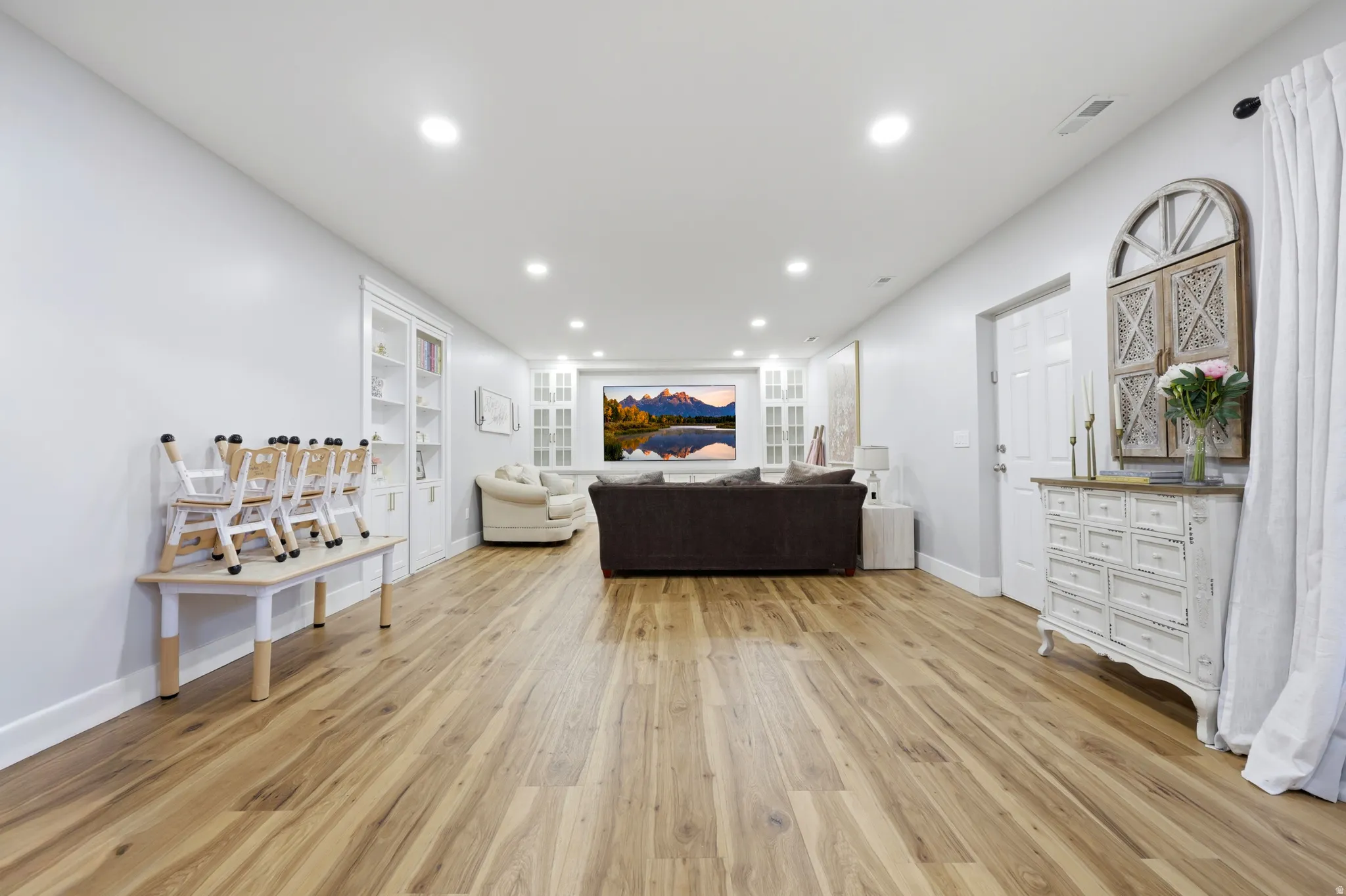 Spacious room featuring wood-finish flooring, recessed lighting, and white walls