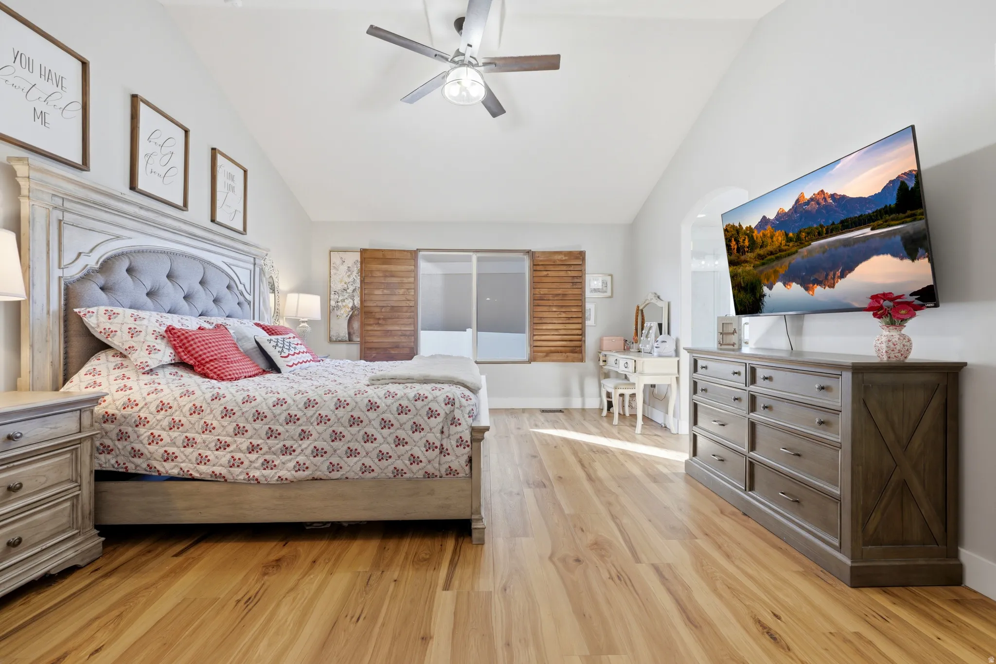Spacious room featuring vaulted ceilings, wood-finish flooring, and a ceiling fan