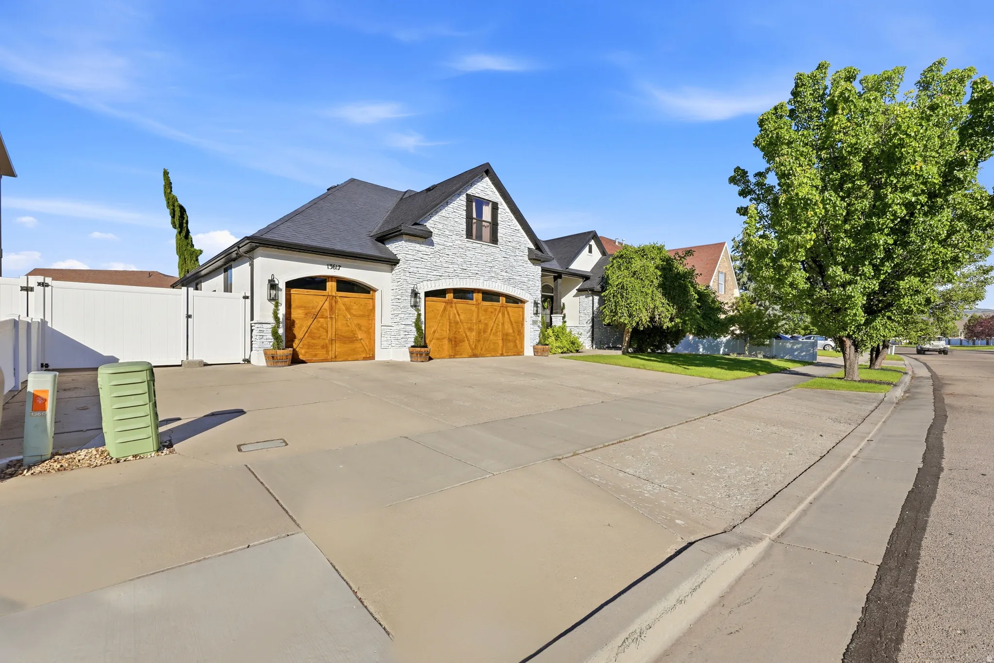Contemporary exterior featuring white painted brick and stucco, dark shingle roofing, and two wood-finish garage doors