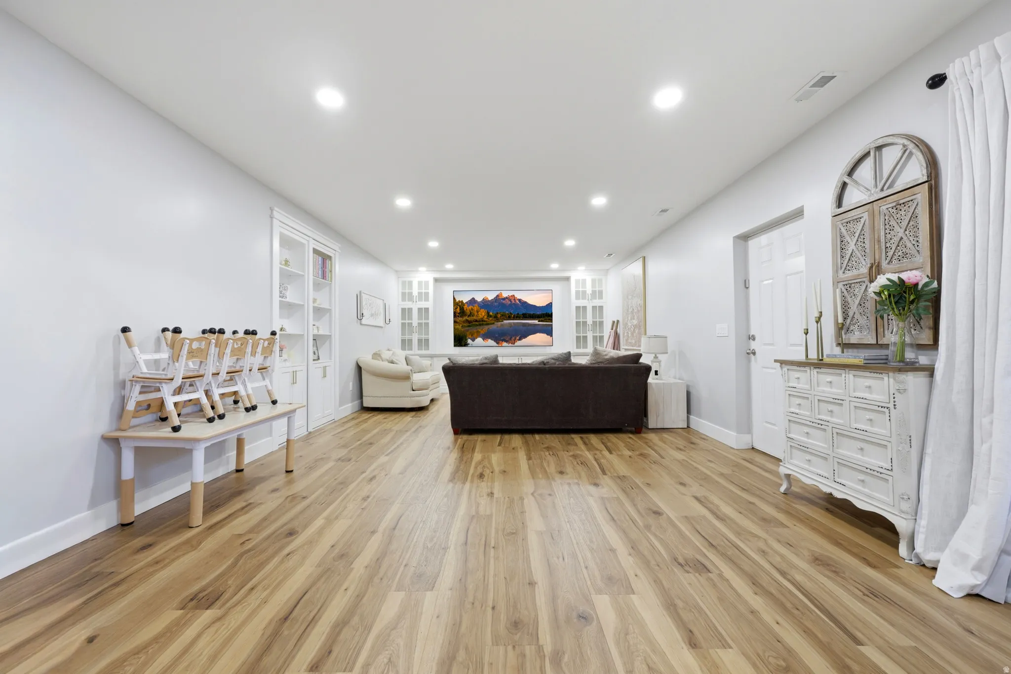 Spacious room featuring wood-finish flooring, recessed lighting, and white baseboards