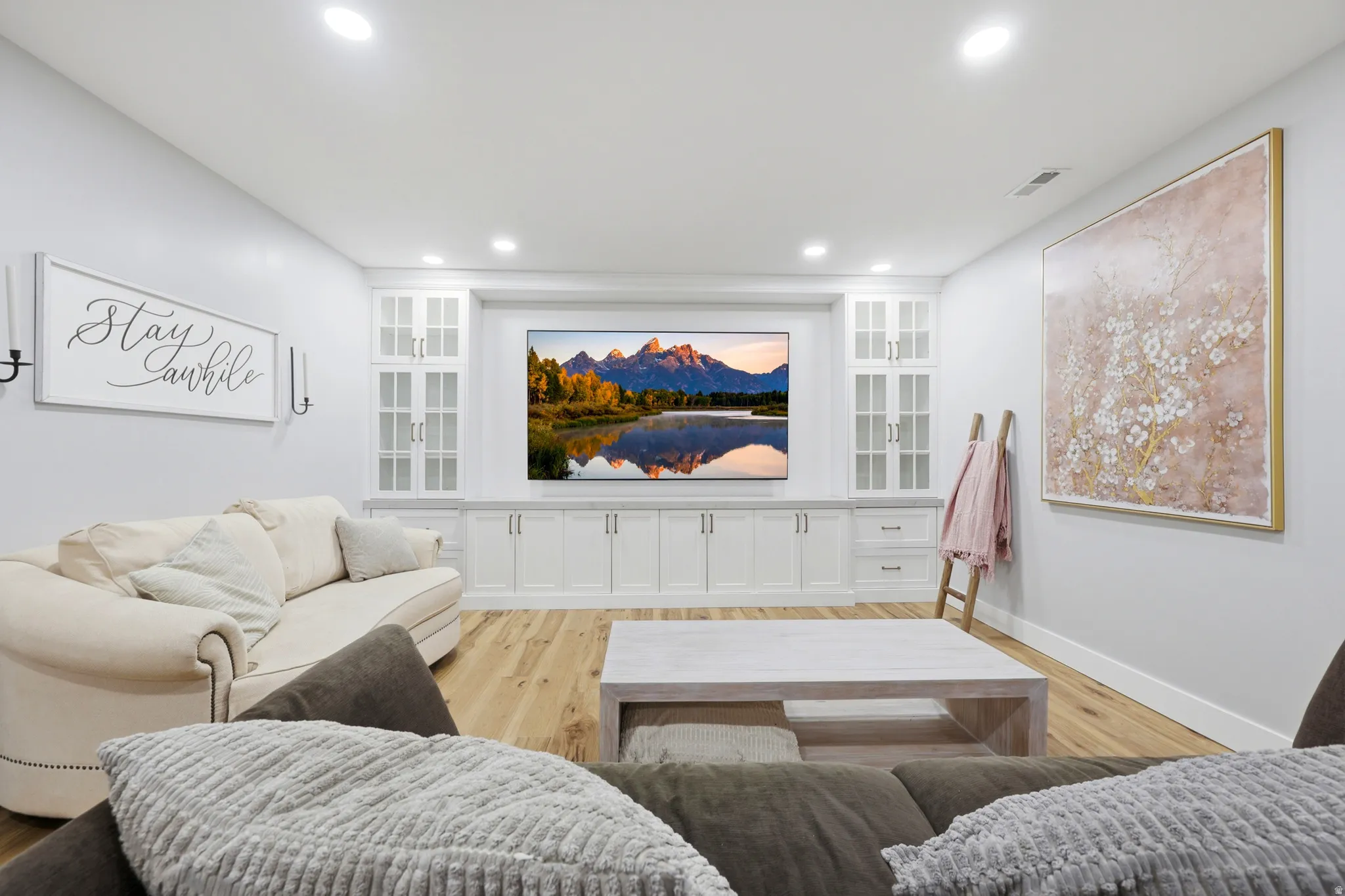 Built-in entertainment center with white cabinetry, glass-front upper cabinets, and integrated lighting