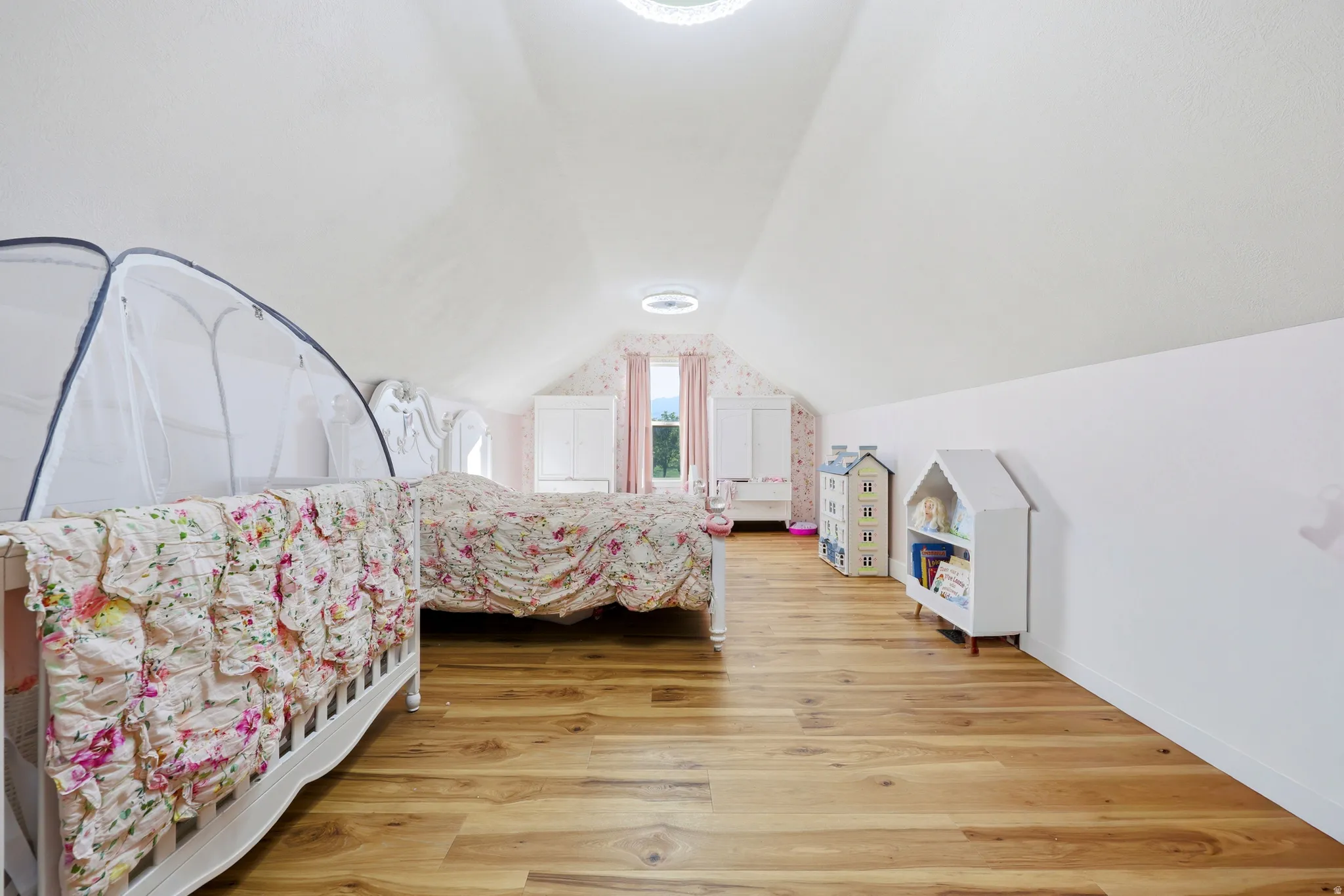 Attic space featuring wood-finish flooring, white walls, and a vaulted ceiling with recessed lighting