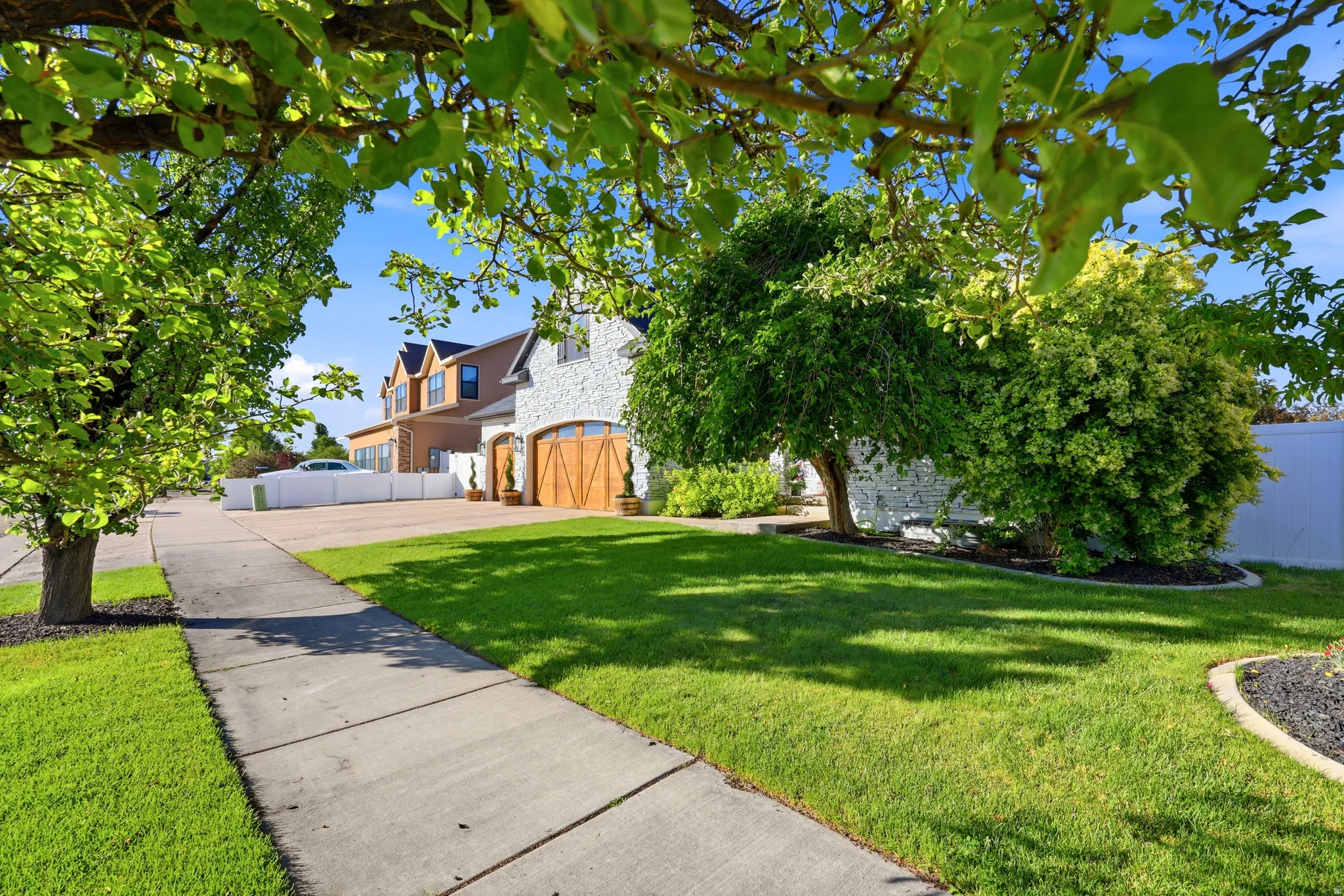 Exterior featuring a stone facade, gabled roofline, and wood-finish garage doors with decorative hardware