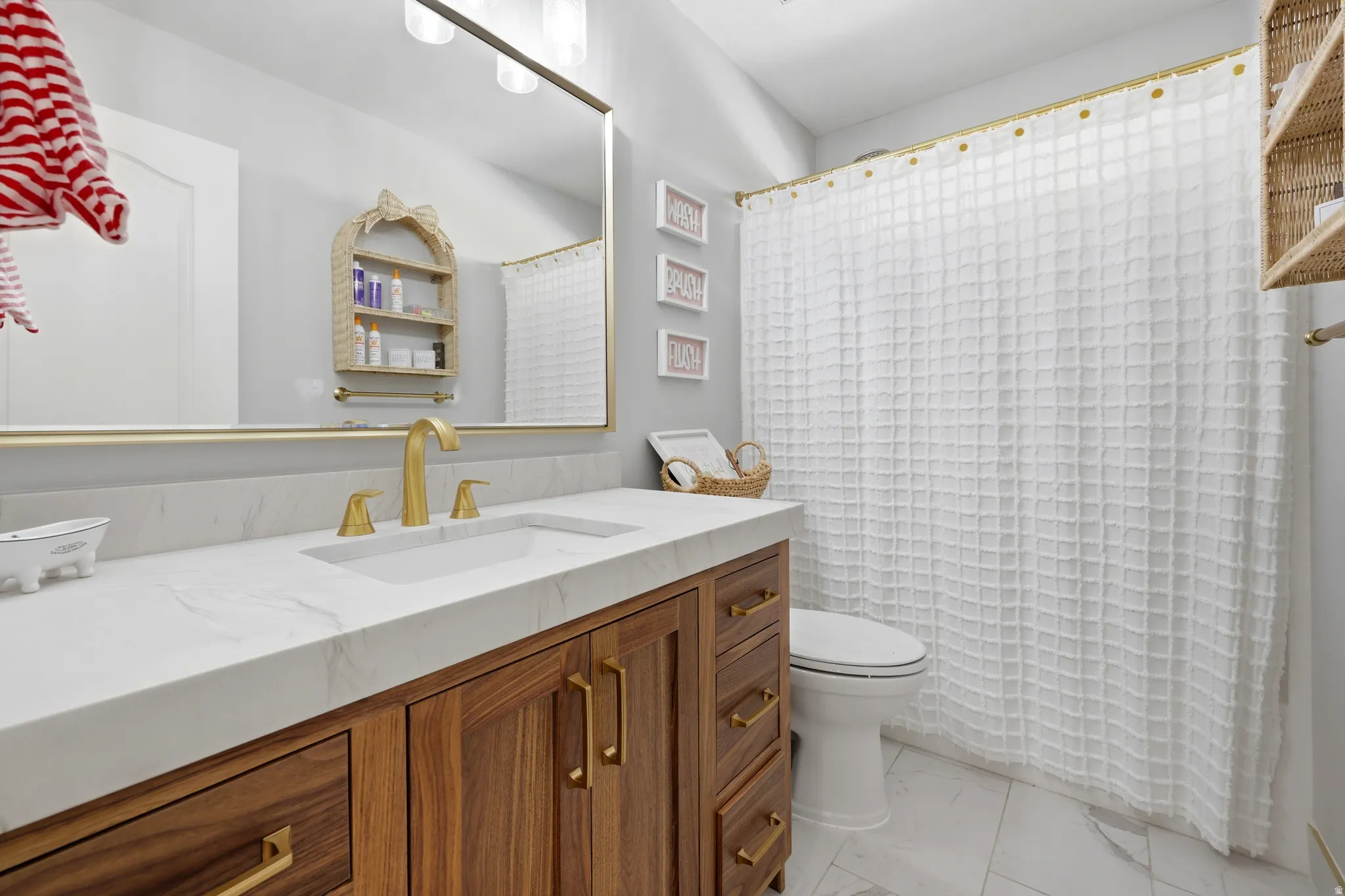 Bathroom vanity featuring a light-toned countertop with integrated sink and brass-finish fixtures