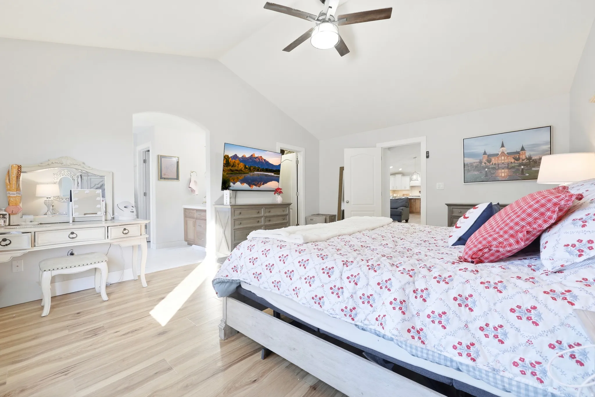 Bright room with vaulted ceilings, wood-finish flooring, and a ceiling fan