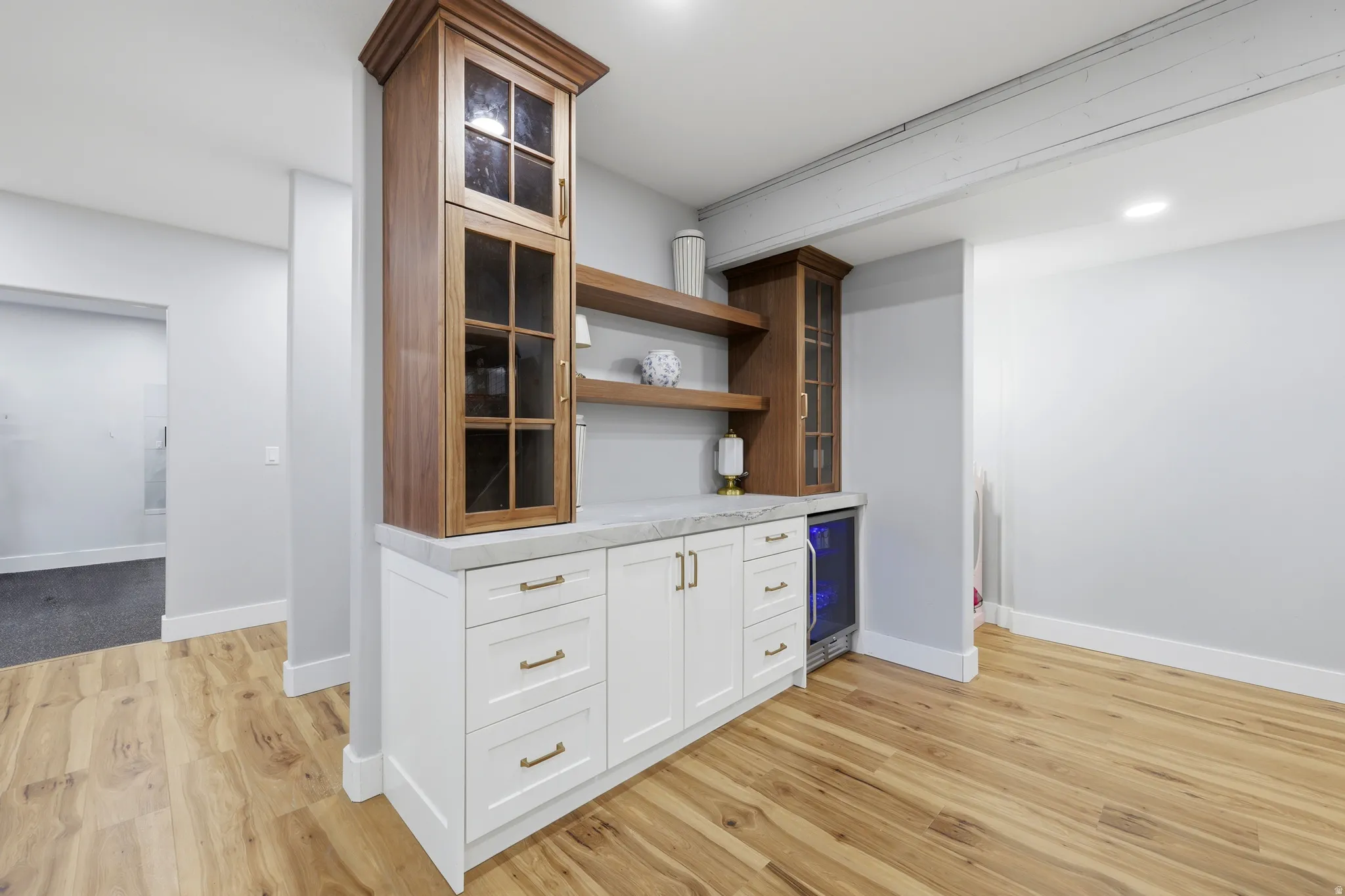 Built-in cabinetry featuring a beverage refrigerator, wood-finish shelving, and a light-toned countertop