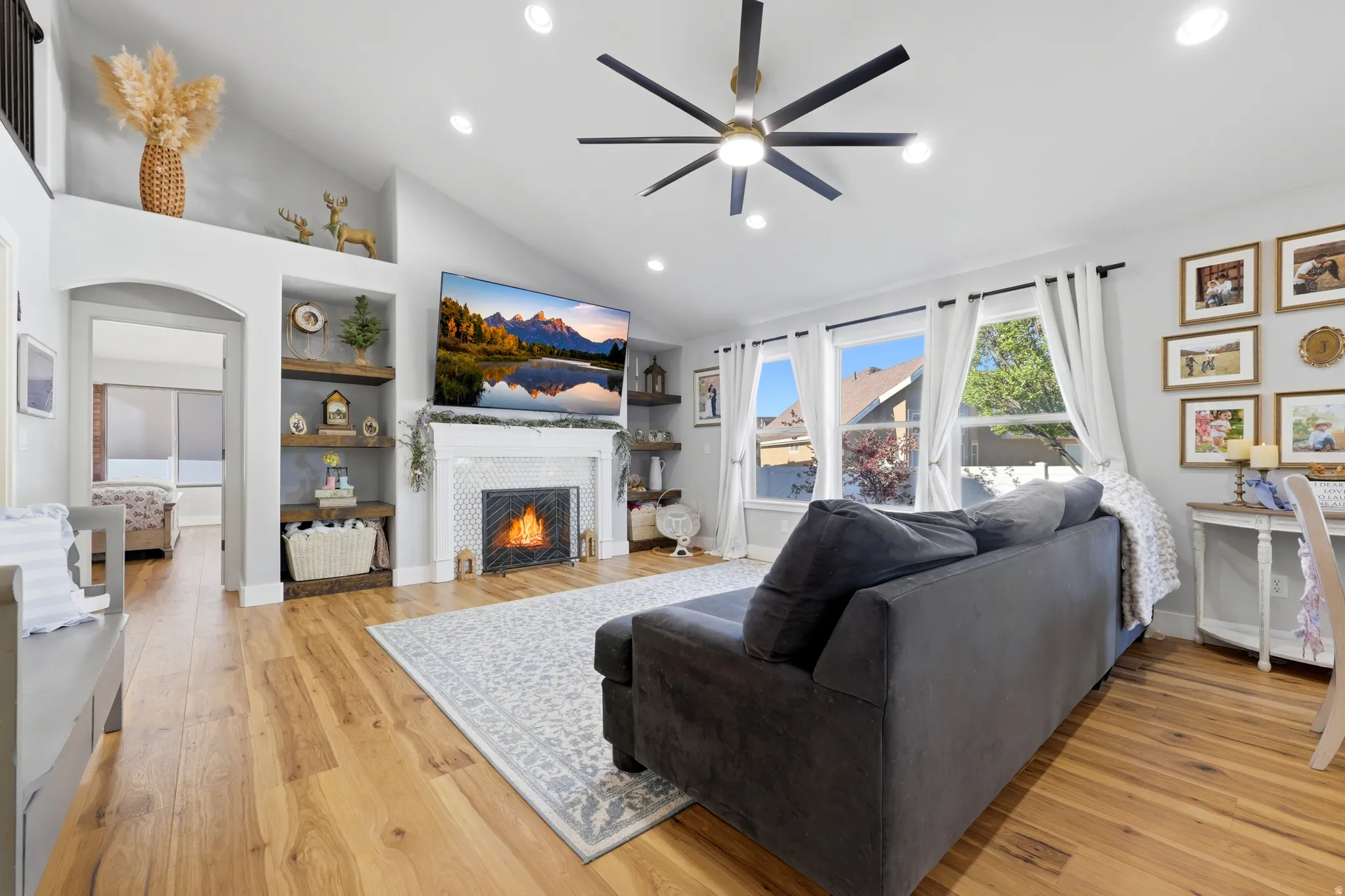 Vaulted ceiling living area featuring recessed lighting, a contemporary ceiling fan, and wood-finish flooring