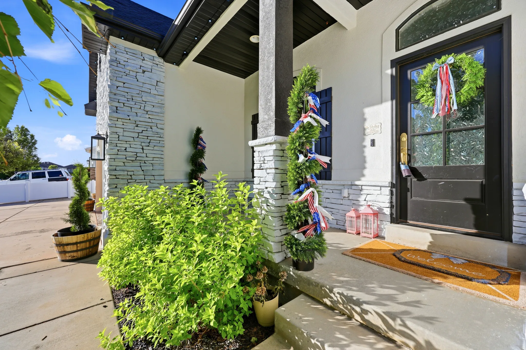 Entryway featuring a dark wood door with glass paneling, an arched transom window, and stone veneer accents