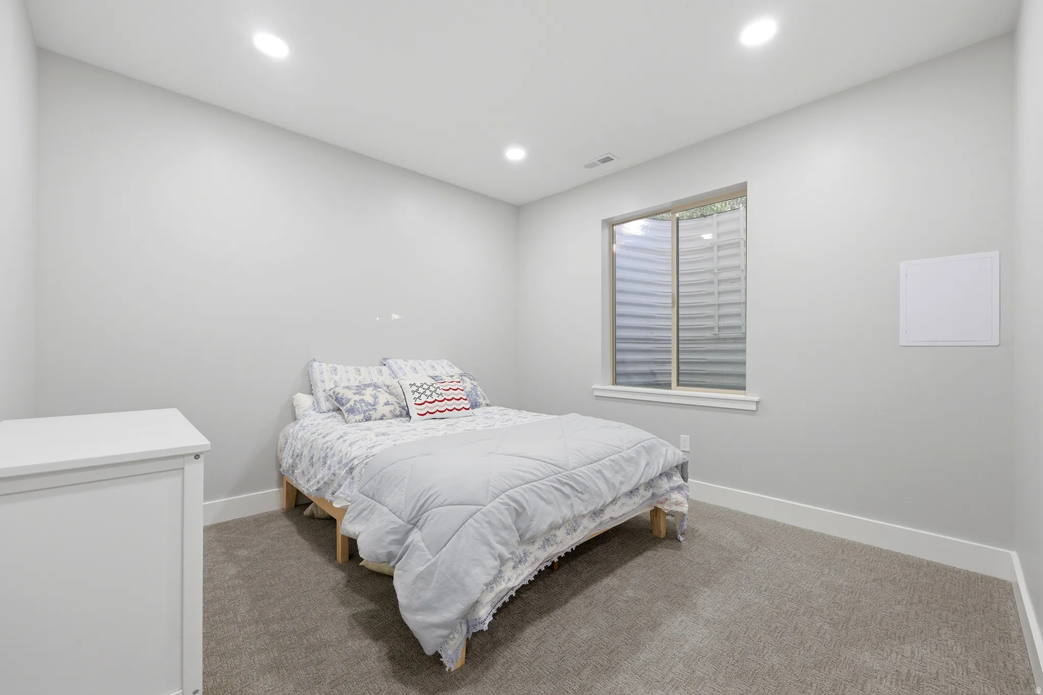 Recessed ceiling lighting illuminates a room featuring a window with a window well