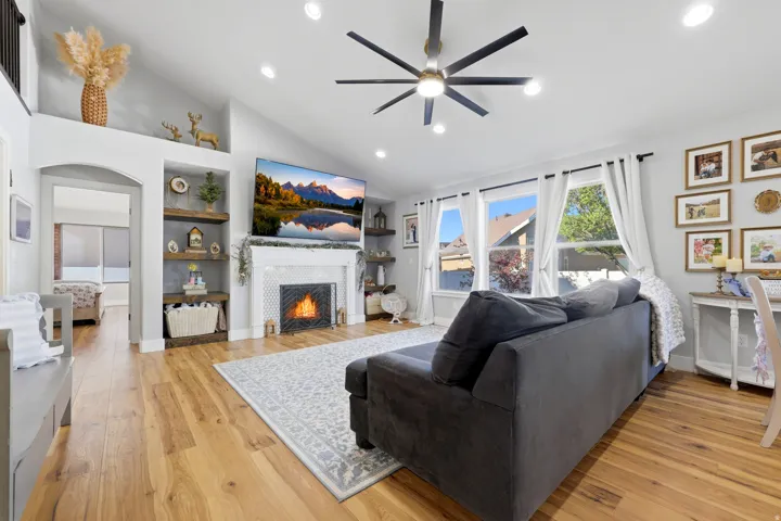 Vaulted ceiling living area featuring recessed lighting, a contemporary ceiling fan, and wood-finish flooring