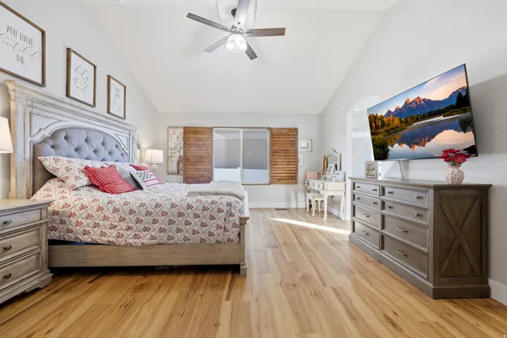 Spacious room featuring vaulted ceilings, wood-finish flooring, and a ceiling fan