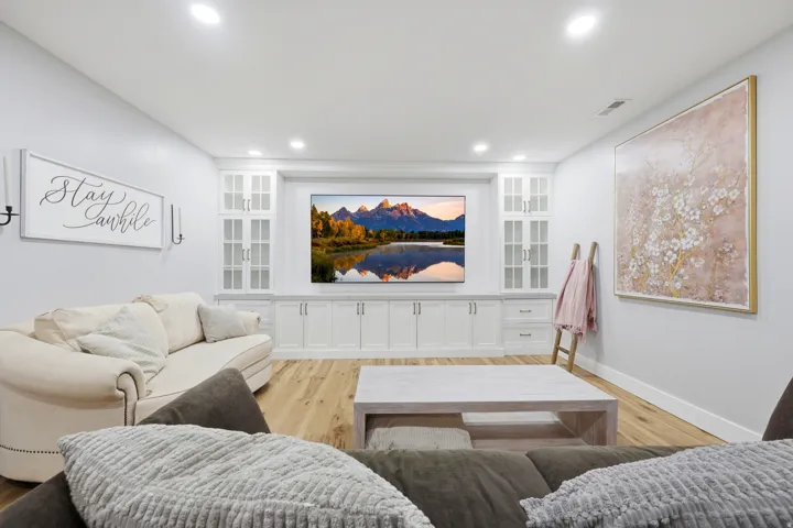Built-in entertainment center with white cabinetry, glass-front upper cabinets, and integrated lighting