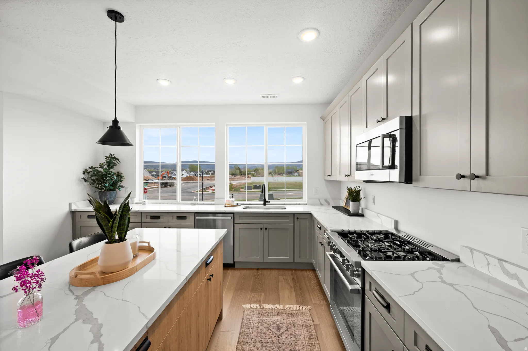 Kitchen featuring light gray cabinetry, wood-finish flooring, and white countertops with gray veining