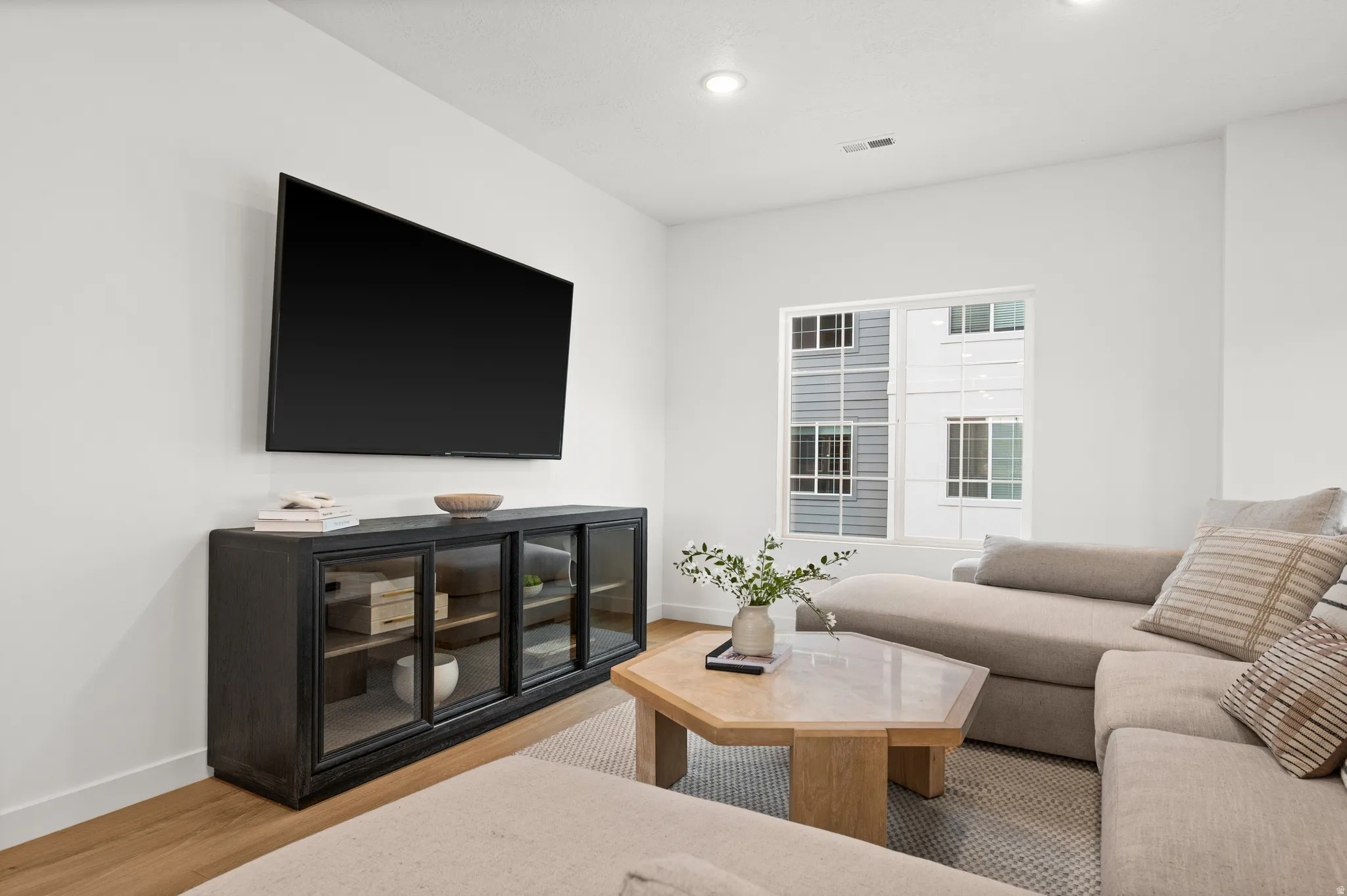 Bright living space featuring recessed lighting, light wood-finish flooring, and a large window
