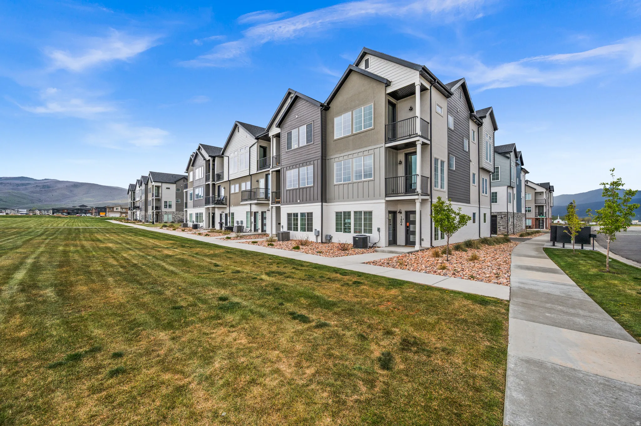 Contemporary townhome-style residences featuring a mix of horizontal and vertical siding, stucco, and stone accents