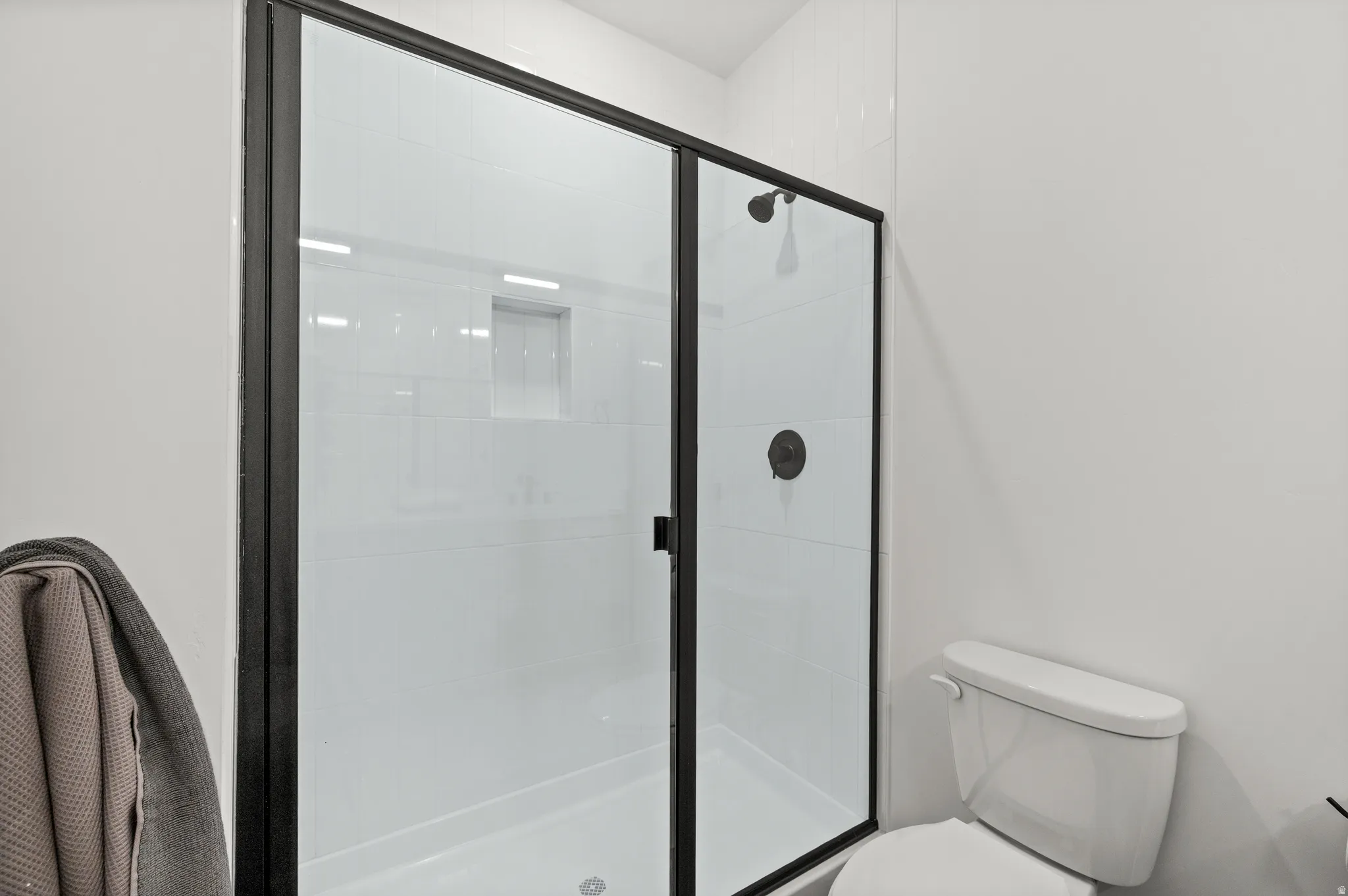 Black-framed glass shower enclosure featuring a built-in shower niche and matte black fixtures