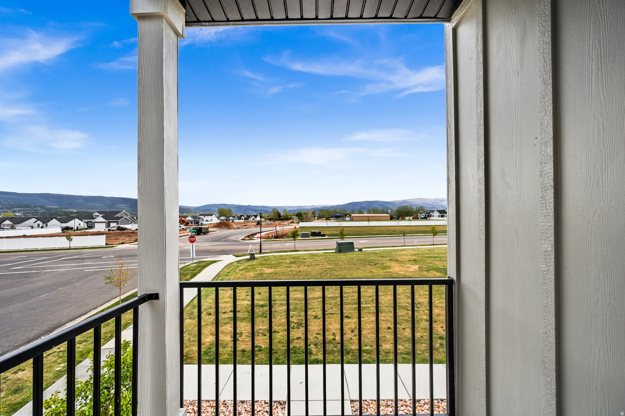 Balcony featuring a black wrought iron railing, white column, and white siding
