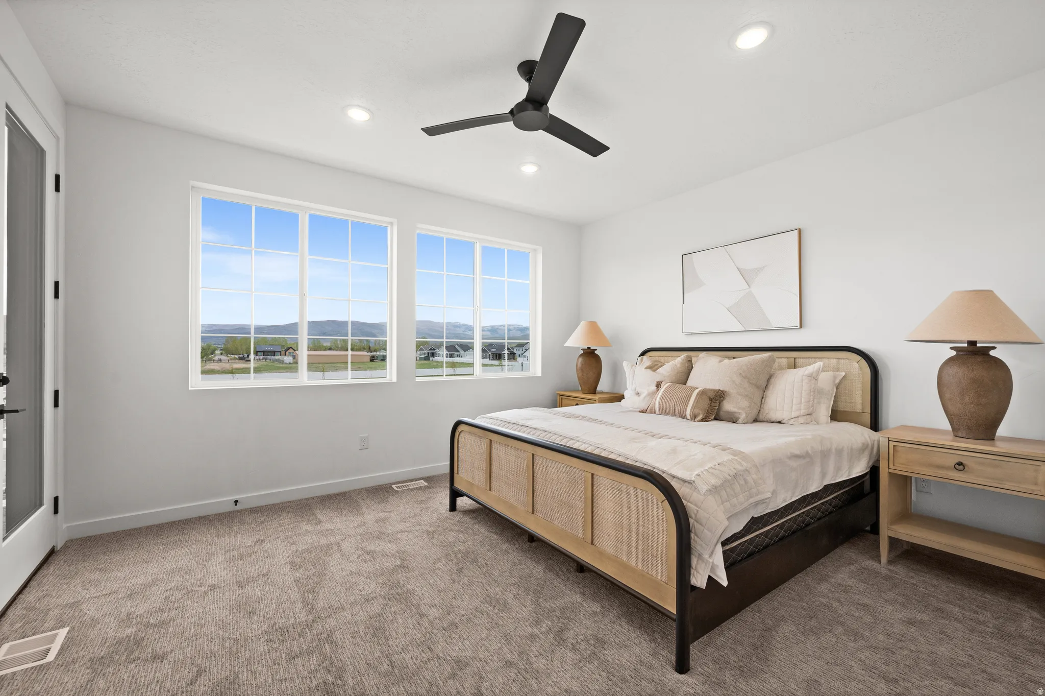 Bright room featuring two large grid-pattern windows, recessed lighting, and a ceiling fan with matte black finish