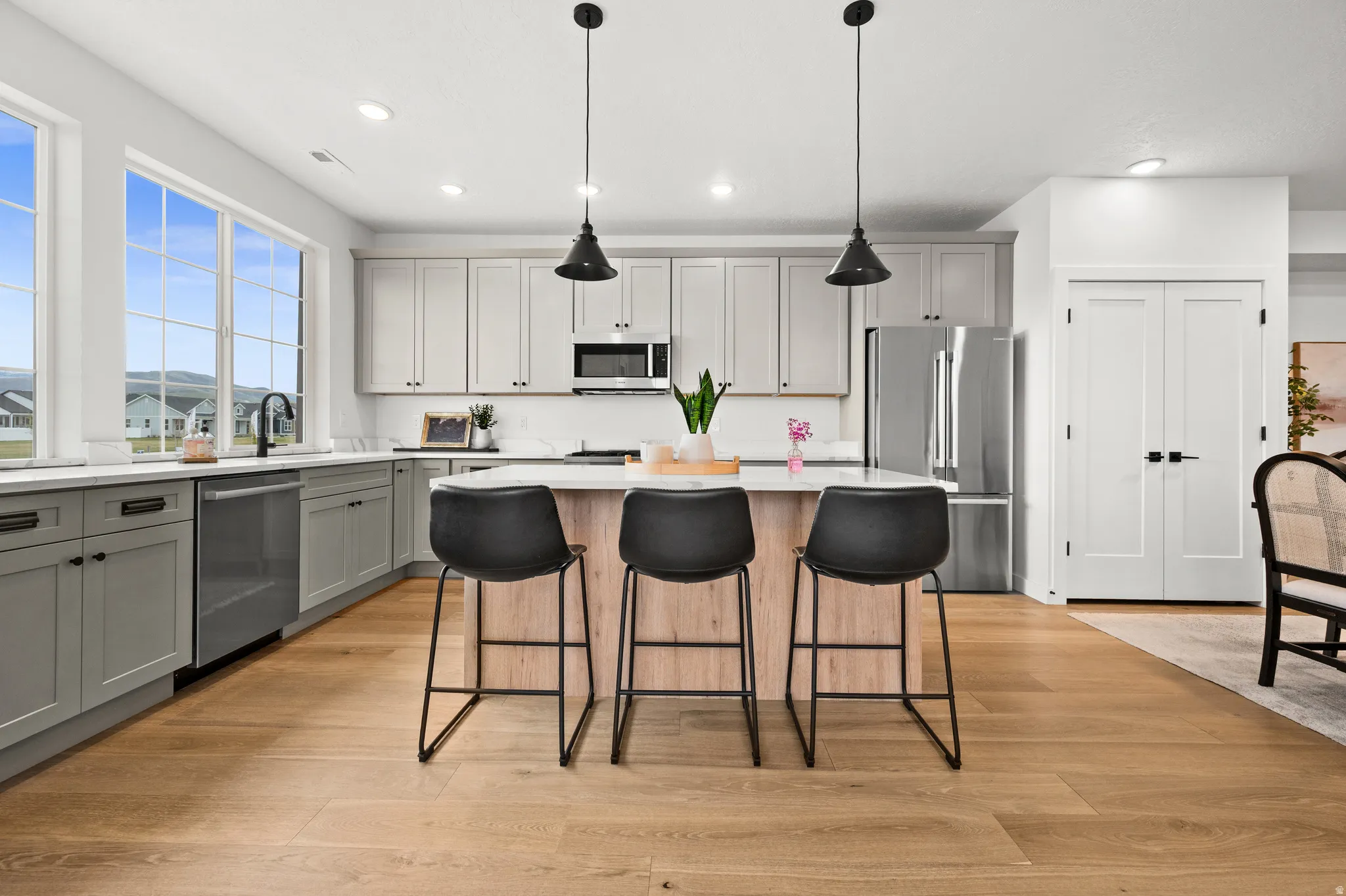 Modern kitchen featuring light wood-finish flooring, a two-tone cabinetry scheme, and a central island with countertop seating