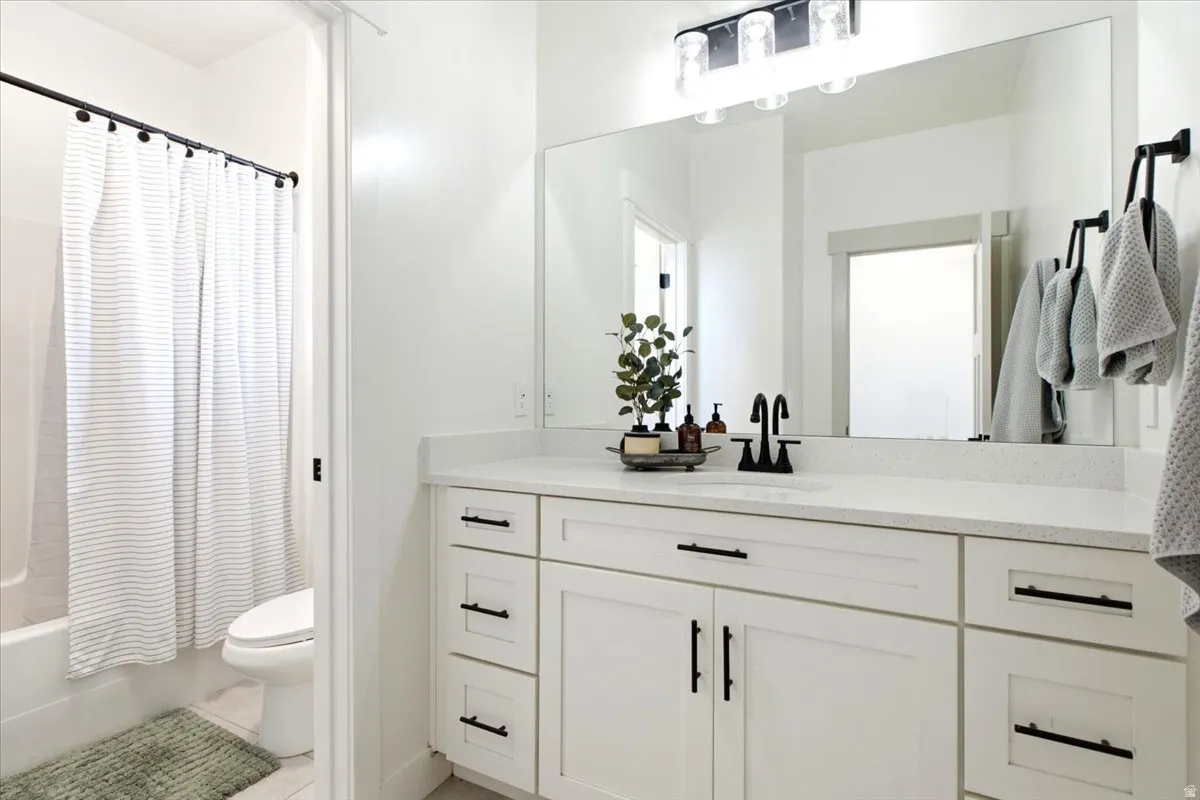 Contemporary bathroom featuring a white vanity with shaker-style cabinetry, black hardware, and a light-colored countertop