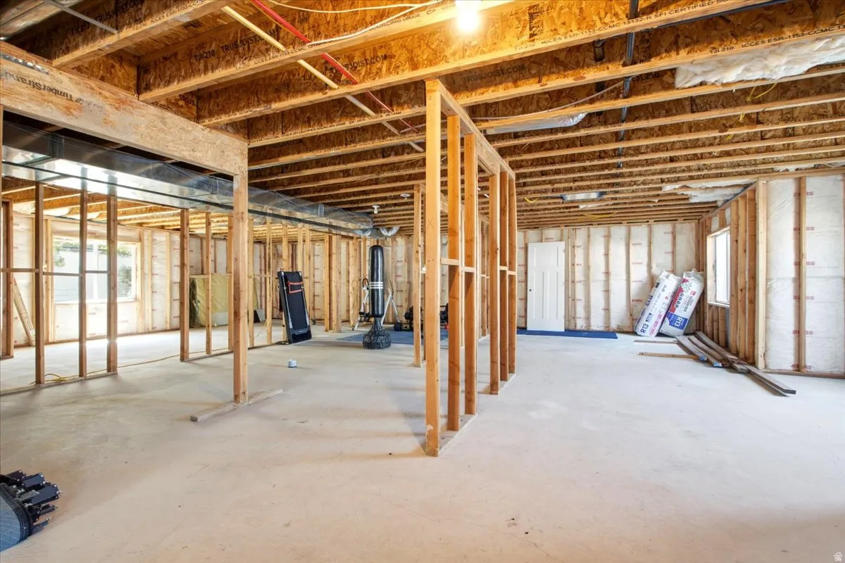 Unfinished basement featuring exposed wood framing, concrete flooring, and visible ceiling joists