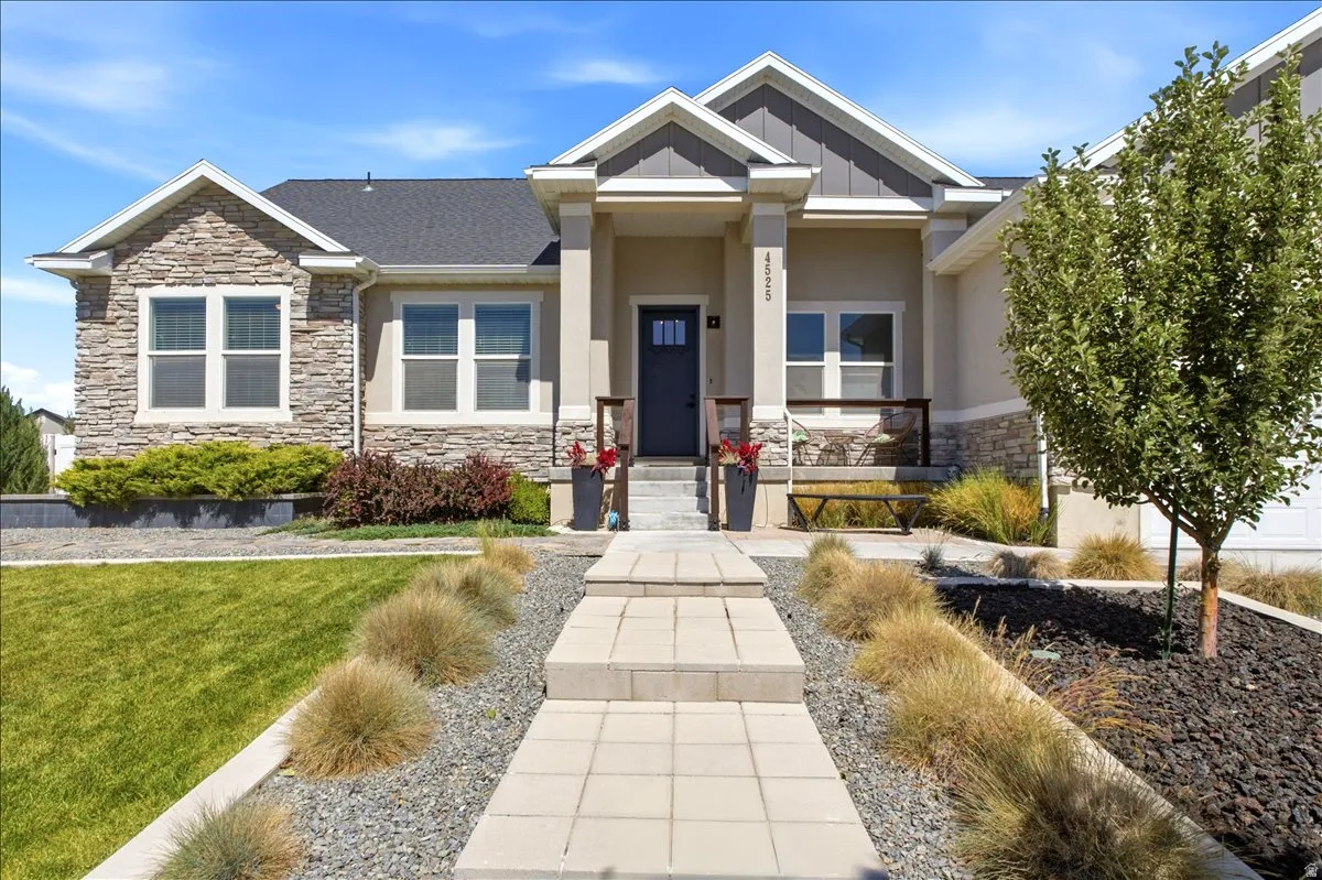 Stone and stucco exterior featuring a covered entry, dark-paneled door, and a concrete paver walkway