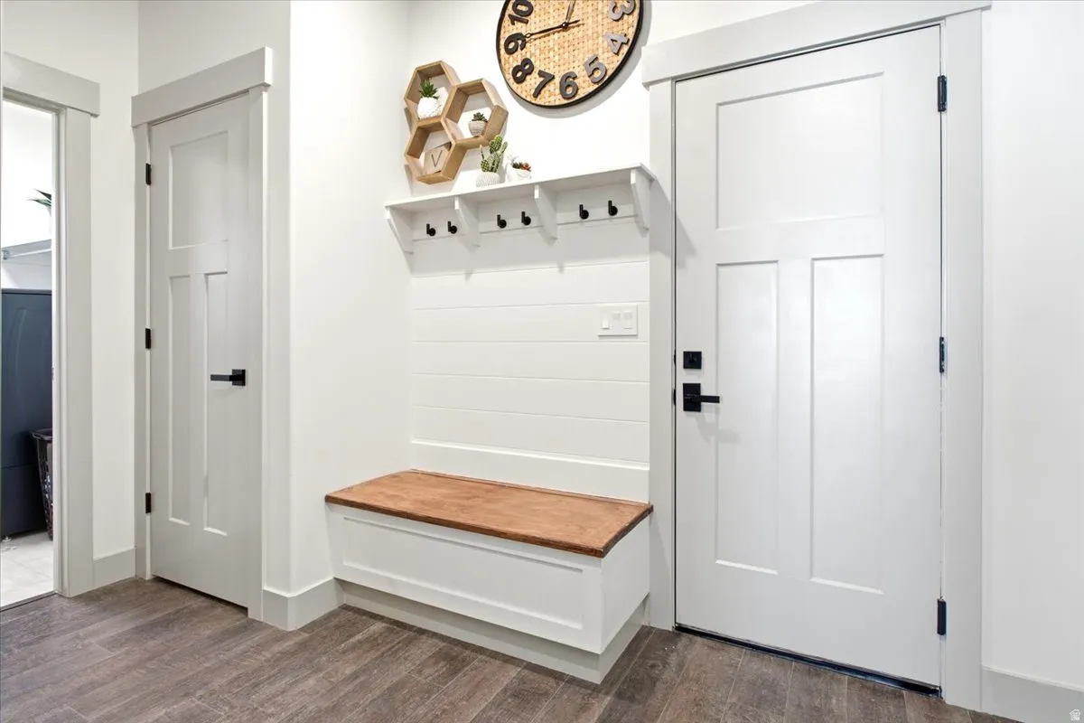 Entryway featuring a built-in bench with a wood-finish top, white shiplap-style wall paneling, and a white coat rack with black hooks
