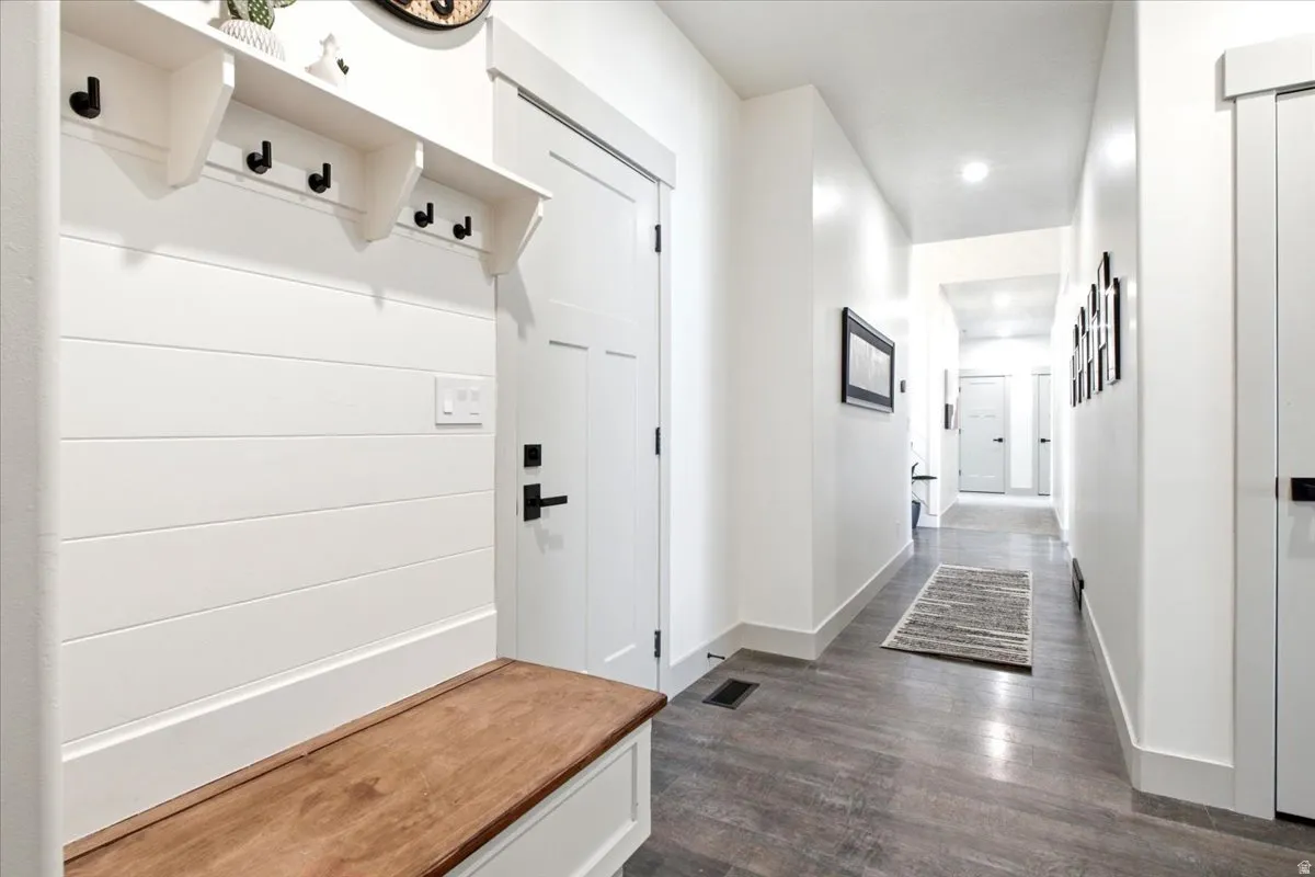 Entryway mudroom featuring a built-in bench with a wood-finish top, white shiplap paneling, and integrated coat hooks
