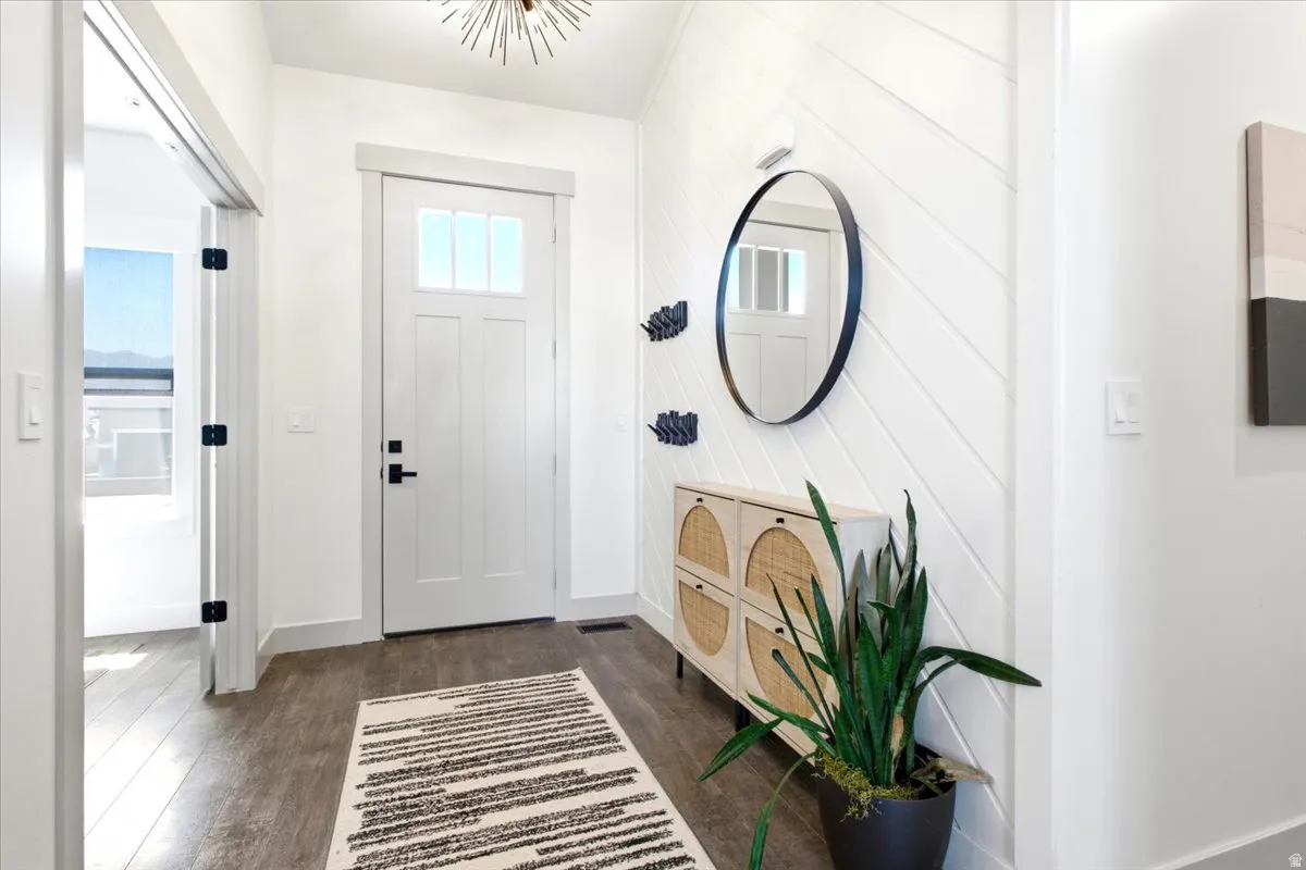 Inviting entryway with a white paneled front door, overhead light fixture, wood-finish flooring, and shiplap accent wall