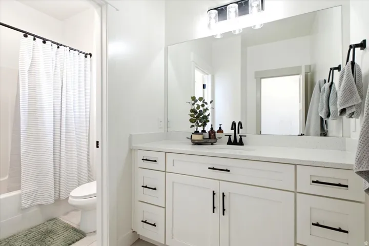 Contemporary bathroom featuring a white vanity with shaker-style cabinetry, black hardware, and a light-colored countertop