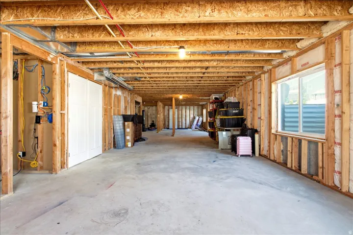 Unfinished lower level with exposed wood framing, concrete flooring, and a large window
