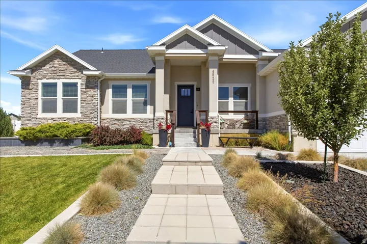 Stone and stucco exterior featuring a covered entry, dark-paneled door, and a concrete paver walkway